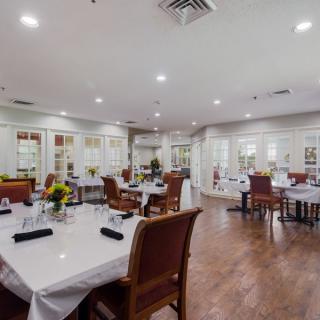 A spacious and elegantly decorated restaurant dining area with neatly arranged tables and chairs.