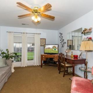 A cozy living room with a ceiling fan, television, and comfortable furniture.