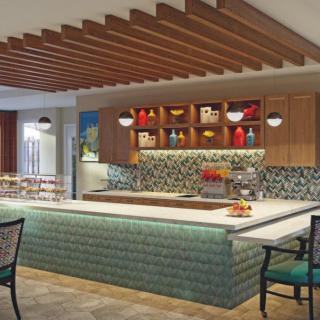 A modern kitchen with an island counter, colorful backsplash, and wooden ceiling beams.