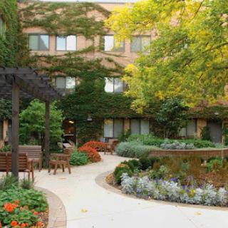A serene garden area featuring a winding pathway, lush greenery, and comfortable seating.