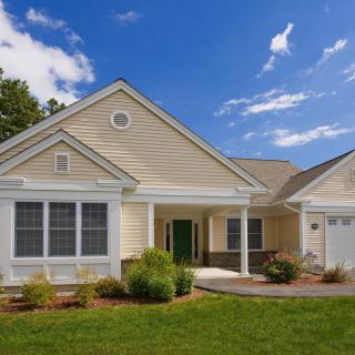 A charming suburban house with a well-maintained lawn under a clear blue sky.
