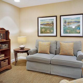 A cozy living room with a comfortable sofa, decorative artwork, and a well-stocked bookshelf.
