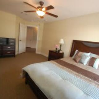 A cozy bedroom with a large bed, wooden furniture, and a ceiling fan.