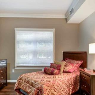 A cozy bedroom with a single bed, decorated in warm tones and featuring a window with blinds.