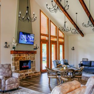 A cozy living room with a stone fireplace, vaulted ceiling, and elegant chandeliers.
