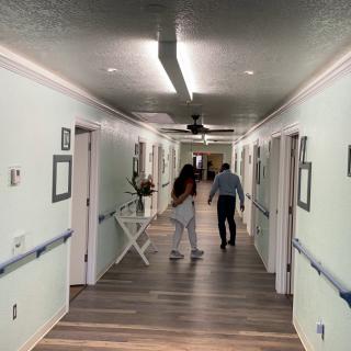 Two people walk down a hallway in a healthcare facility.