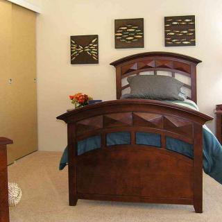 A cozy bedroom with a wooden bedframe and elegant wall decor.