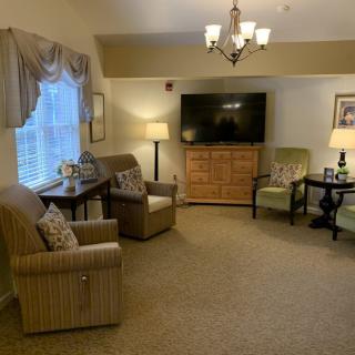 A cozy living room with armchairs, a large television, and soft lighting.