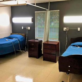 A view of a hospital patient room with two beds and bedside tables.