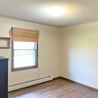 An empty room with wooden floors and a window with blinds.
