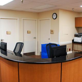 A reception desk in an office setting with computer monitors and chairs.