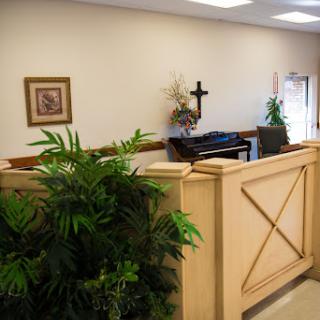 A serene interior space featuring decorative plants, artwork, and a piano.