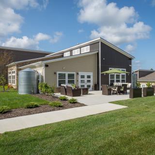 A modern house with a well-manicured lawn and outdoor patio area under a partly cloudy sky.