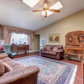 A cozy living room with leather sofas, a colorful area rug, and wooden furniture under a ceiling fan.