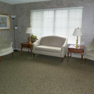 A simple and spacious living room featuring a sofa, two chairs, and side tables with lamps.
