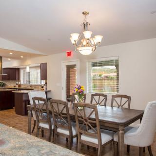 A modern open-concept dining room and kitchen featuring a large dining table with chairs and a chandelier.