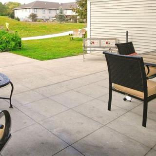 A spacious backyard patio with outdoor furniture overlooking a well-maintained lawn.