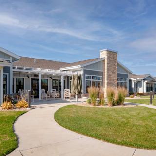 A modern residential building with a landscaped lawn and walkway, set under a clear blue sky.