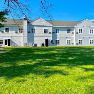 A residential building with a green lawn and clear blue sky.
