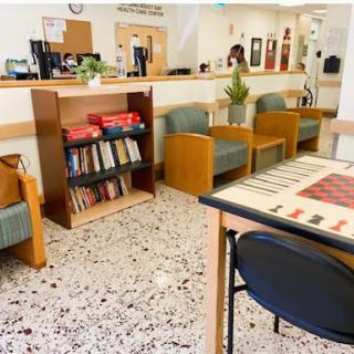 A cozy waiting area featuring comfortable seating, a bookshelf filled with books, and a checkers game for guests to enjoy.
