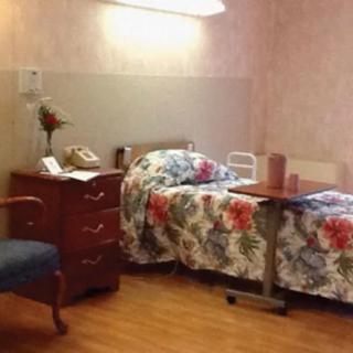 A hospital or nursing home room with a bed and furniture.