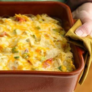 A freshly baked casserole with melted cheese and vegetables, being handled with an oven mitt.