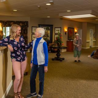Two people having a conversation in the lobby of a senior living facility.