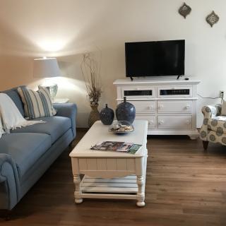 Cozy living room with a blue sofa, white coffee table, and TV stand.