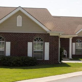 A suburban brick house with a well-maintained lawn and large windows.