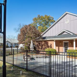 A charming residential home with a fenced patio area under a bright blue sky.