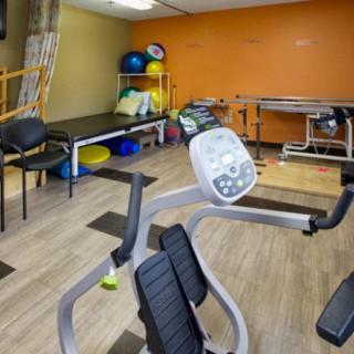 A physical therapy room equipped with an exercise bike, therapy tables, and various rehabilitation tools.