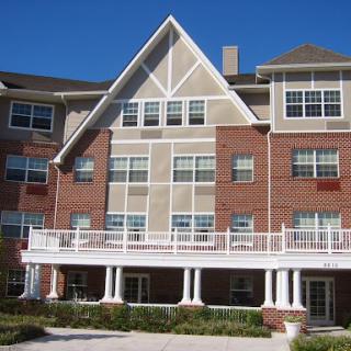 A multi-story residential building featuring a combination of brick and siding, with spacious balconies and numerous windows.