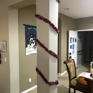A warmly decorated dining area with a column wrapped in tinsel, creating a festive atmosphere.