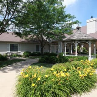 A charming house with a well-maintained garden featuring a gazebo and colorful flowers along the driveway.