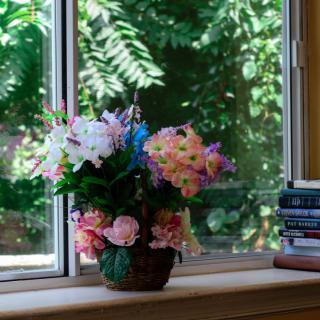 A bouquet of colorful flowers placed next to stacked books on a windowsill.