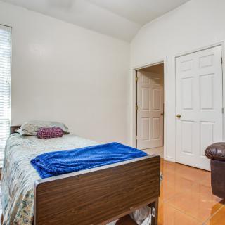 A minimalist bedroom with a single bed and hardwood flooring.