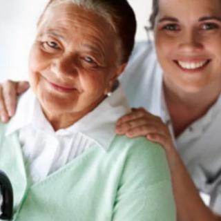 An elderly woman with her caregiver smiling together.