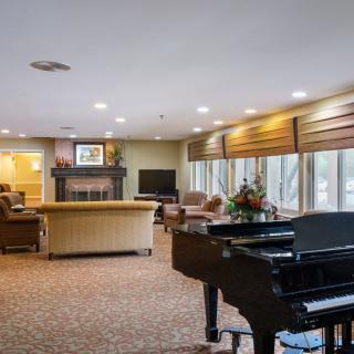 A spacious living room featuring a grand piano, comfortable seating, a fireplace, and a large television.