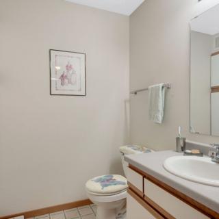 A clean and simple bathroom with a sink, toilet, mirror, and wall artwork.
