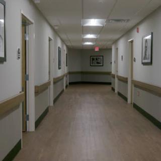 A quiet hallway in a hospital, featuring closed doors and framed pictures on the walls.