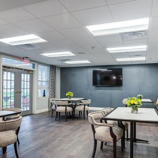 A modern dining area with tables, chairs, and decorative flowers under bright lighting.