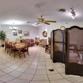 A spacious living and dining area featuring wooden furniture, tile flooring, a ceiling fan, and decorative elements.