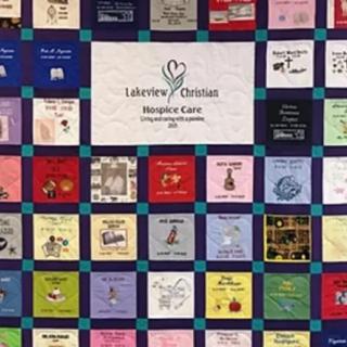 A colorful patchwork quilt featuring various fabric squares, each with unique designs and messages, centered around a hospice care theme.