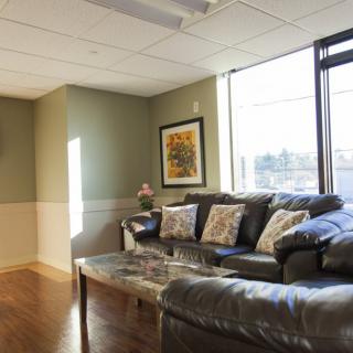 A cozy living room with a comfortable sofa and a coffee table, illuminated by natural light streaming through large windows.
