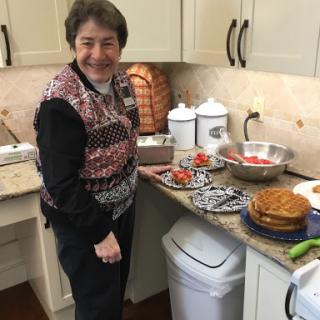 A woman happily preparing a meal in a cozy kitchen, surrounded by delicious food.