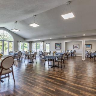 A spacious and well-lit dining room with modern furnishings and large windows.