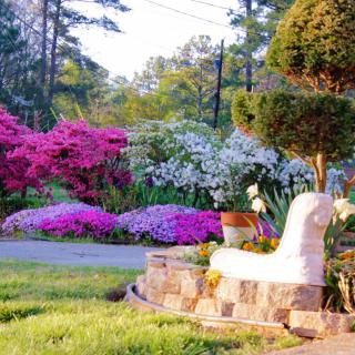 A vibrant garden scene with blooming flowers and a decorative sculpture.