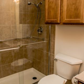 A clean and modern bathroom featuring a shower, toilet, and wooden cabinetry.