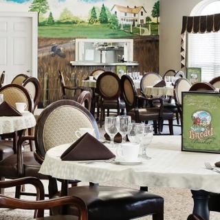 An elegant dining area with neatly set tables, featuring a scenic mural on the wall.