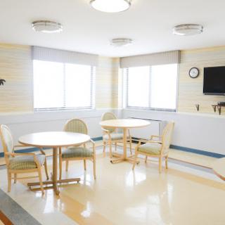 A bright and spacious waiting area in a hospital with tables and chairs.